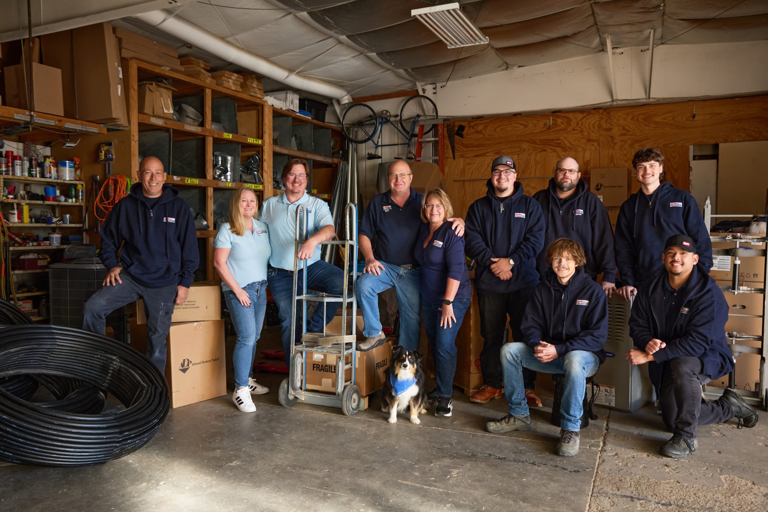 The Harley's Heating and Air Conditioning team gathered in their shop in Lincoln, Nebraska, three generations of the Shortridge family alongside their technicians and the company dog